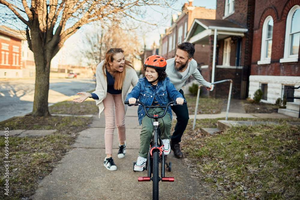 Fototapeta premium Boy learning to ride a bike with supportive parents