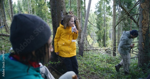 Group of travelers resting in camp after long walking trek in the mountains. Multiethnic young hikers talking, having snack in the forest during tourist trip or hike in autumn. Active leisure concept.