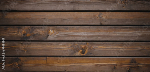 This image shows a close-up view of a wooden surface, characterized by horizontal planks with visible grains and textures. The wood has a dark brown color, and the lines between the planks are clearly