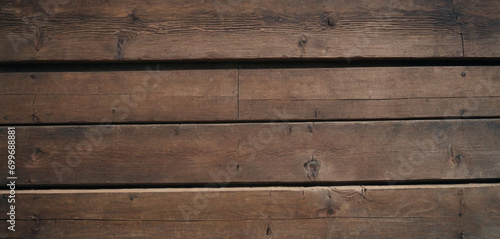 This image shows a close-up view of a wooden surface, characterized by horizontal planks with visible grains and textures. The wood has a dark brown color, and the lines between the planks are clearly