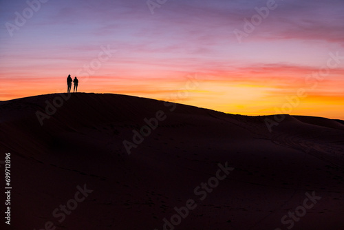朝焼けの砂丘に立つカップルのシルエット