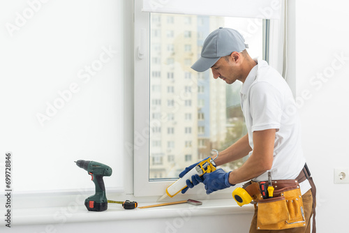 Using drill by installing windows. Repairman is working indoors in the modern room
