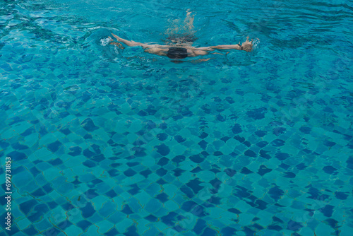 Top view of young man swimming front crawl in blue water