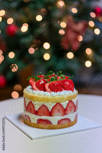 Beautifully lit Christmas tree and delicious-looking strawberry cake