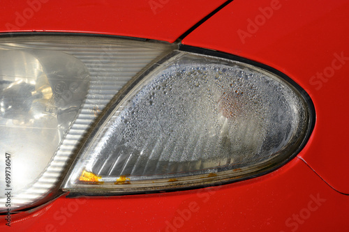 Water got into the headlights of the red car and the headlights in need of maintenance and replacement. Due to severe weather  old car headlights turn yellow and are rarely cleaned