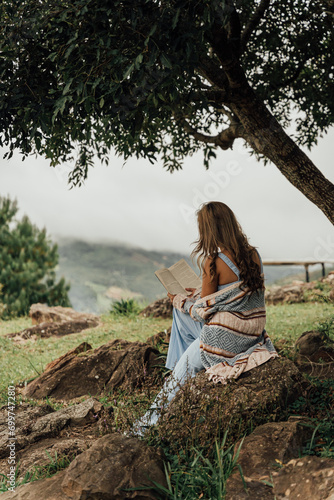 Teenager/woman reading a book on a hill