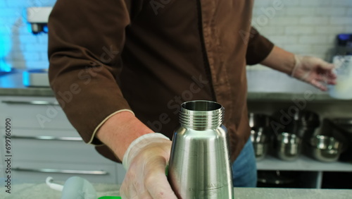 Foto Chef screws lid of whipping siphon on table closeup