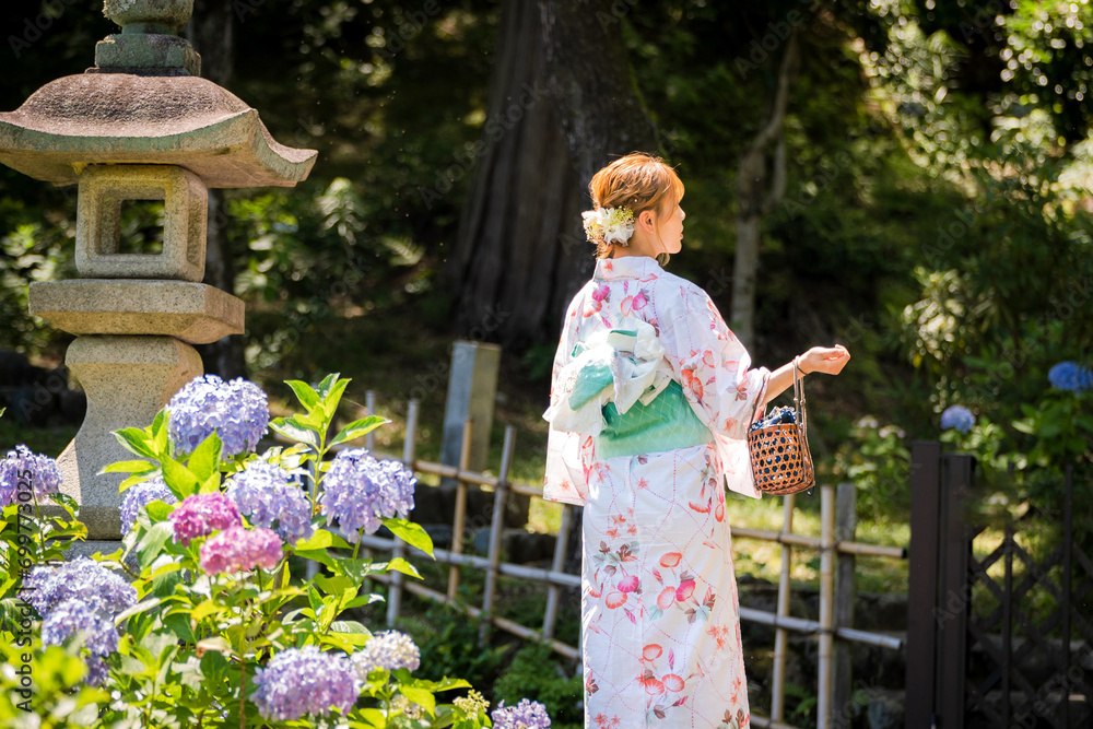 Portrait of a young woman wearing a Japanese yukata summer kimono in a hydrangea garden. Kyoto, Japan. soft blur background. Portrait of a young woman wearing a Japanese yukata summer kimono in a hydrangea garden. Kyoto, Japan. soft blur background.