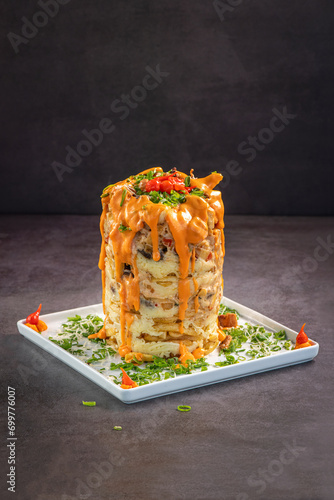 Cheddar French fries tower on grey background.