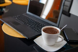 Czarna kawa w białym kubku na tle laptopa