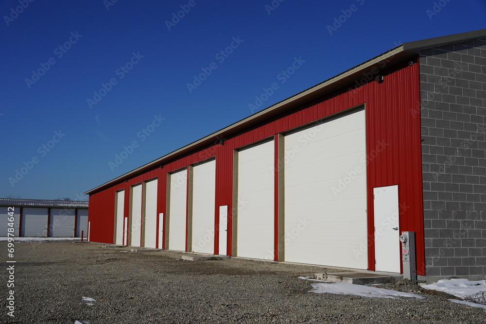 Extra large tall red and white storage units used for the community sit outside during the winter cold.