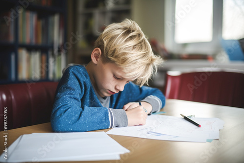 Sad tired child doing his homework sitting. The boy struggles with reading, writing and solving math problems at home. Education, school, learning disability, reading difficulties, dyslexia concept.  photo