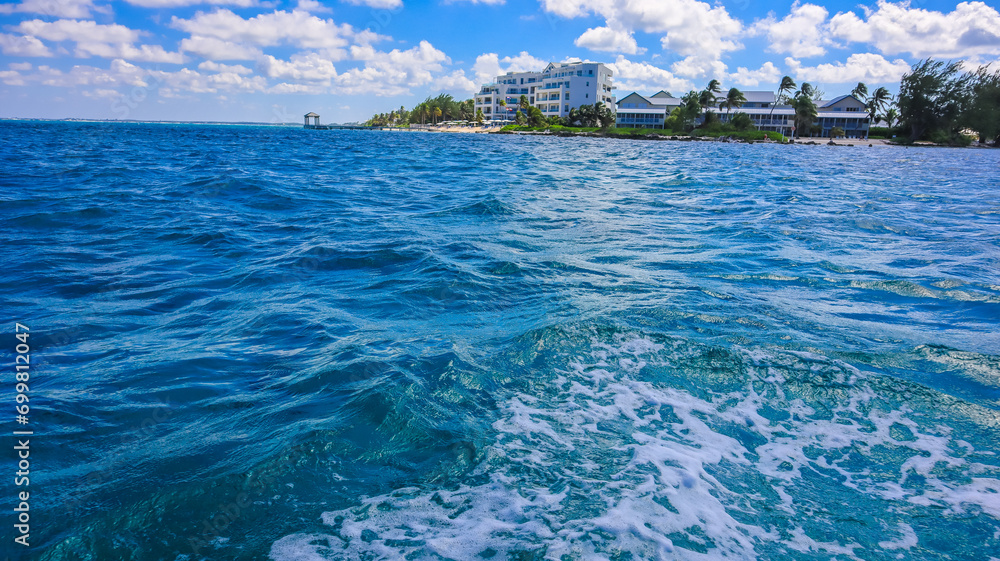 View of the Cayman Islands North Side shore from the pristine blue green turquoise Caribbean sea ocean in Grand Cayman with buildings hotels and greenery plants 