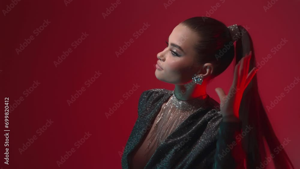 A young elegantly dressed glamorous woman with bright evening makeup, fashionable ponytail and diamond jewelry, dances casually in the light of red lanterns. A young elegantly dressed glamorous woman with bright evening makeup, fashionable ponytail and diamond jewelry, dances casually in the light of red lanterns.