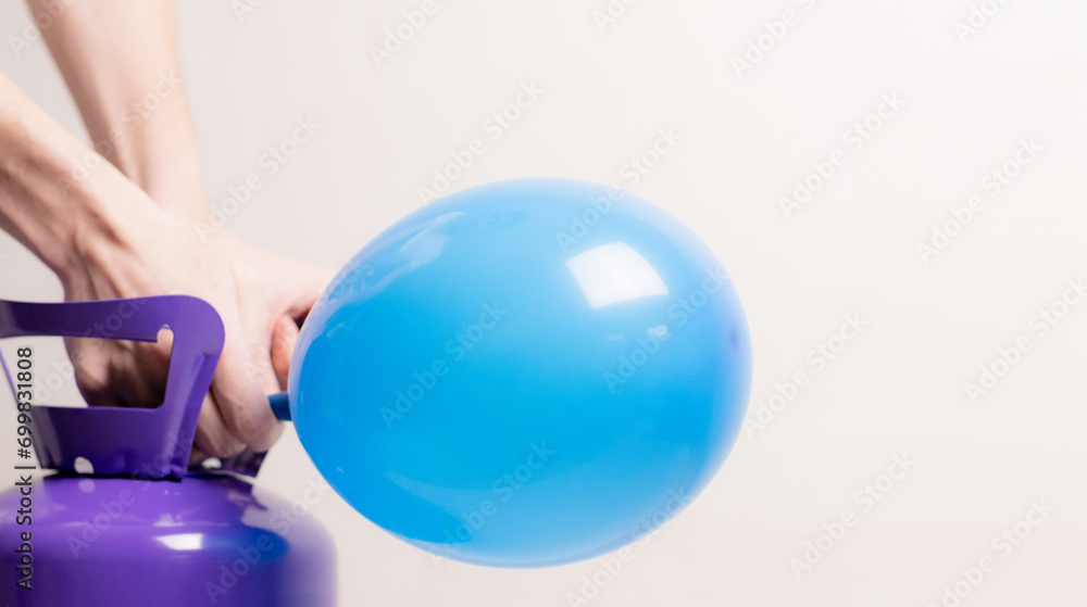 A young guy inflates a balloon with helium.