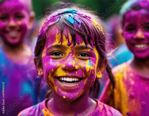 Happy smiling young girl painted in the bright colors of Holi festival