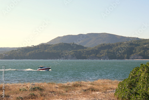 Scenic view of the mouth of the Sado River in Tróia, Portugal, with a boat in the water and the Serra da Arrábida in the background. photo