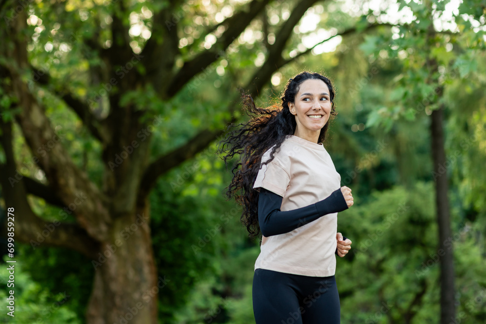 Young beautiful woman running in the evening in the park, hispanic woman with curly hair smiling contentedly, active lifestyle Young beautiful woman running in the evening in the park, hispanic woman with curly hair smiling contentedly, active lifestyle