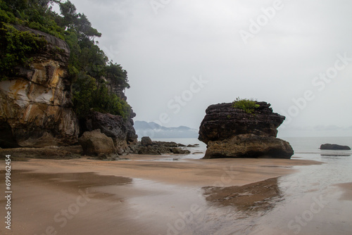 A tranquil beach scene with rock formations and overcast sky