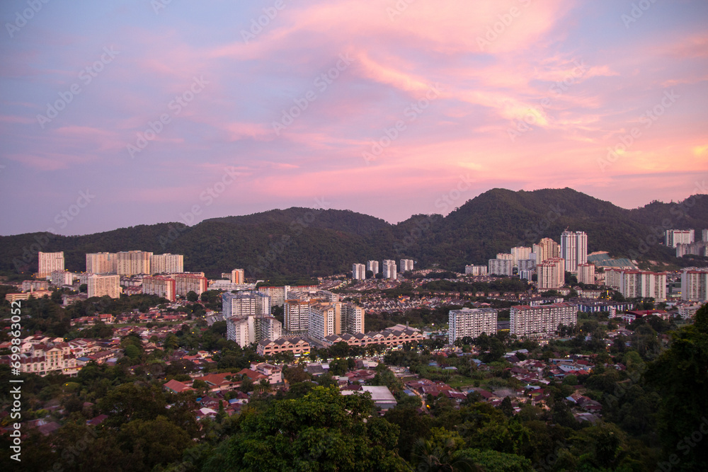 Cityscape at dusk with mountains in the background under a pink-tinted sky