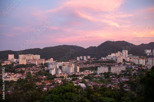 Cityscape at dusk with mountains in the background under a pink-tinted sky © Marcel