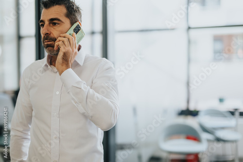 Successful businessman negotiating a deal over the phone in office. photo