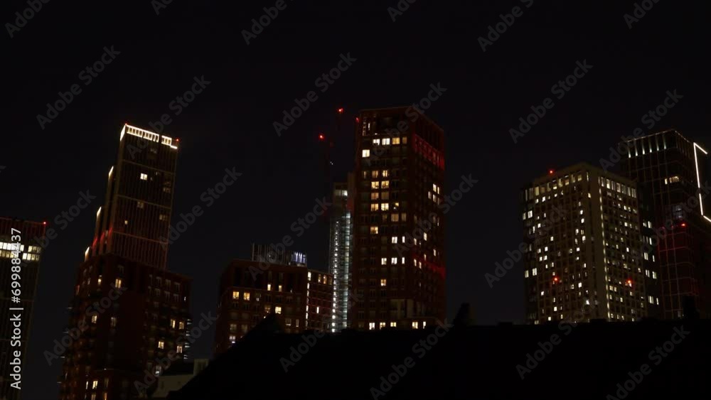 TIME LAPSE: Beautiful cityscape with business and residential buildings in the late evening hours. Lit lights shine through windows of tall urban skyscrapers in London district under dark night sky. TIME LAPSE: Beautiful cityscape with business and residential buildings in the late evening hours. Lit lights shine through windows of tall urban skyscrapers in London district under dark night sky.