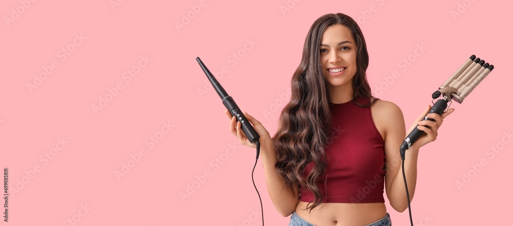 Beautiful young woman holding different curling irons on pink background with space for text