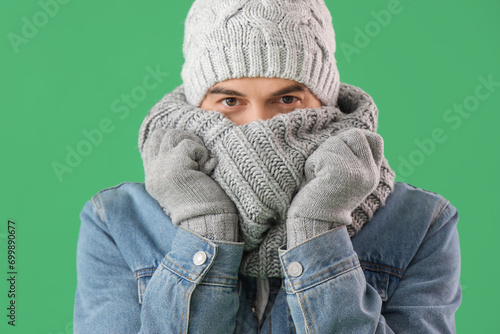 Handsome man in winter clothes on green background, closeup