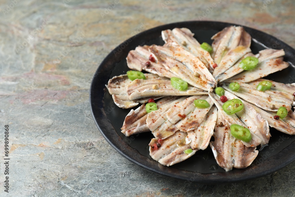 Tasty pickled anchovies with spices on textured table, closeup. Space for text