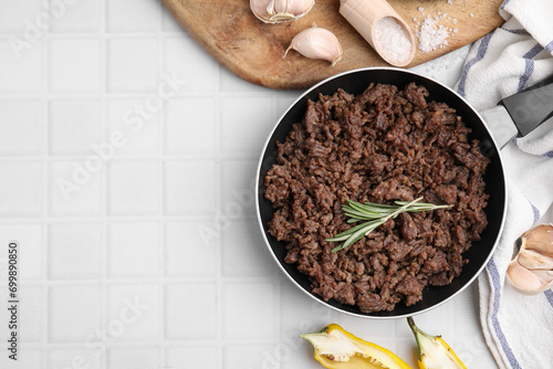 Bilde på lerret Fried ground meat in frying pan and products on white tiled table, flat lay