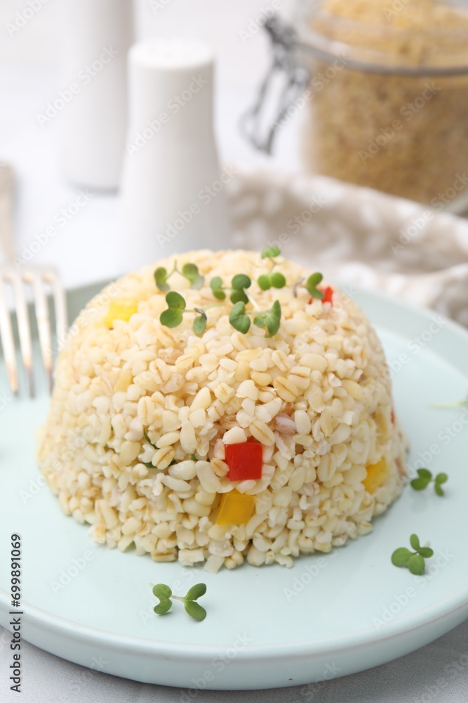 Delicious bulgur with vegetables and microgreens on table, closeup