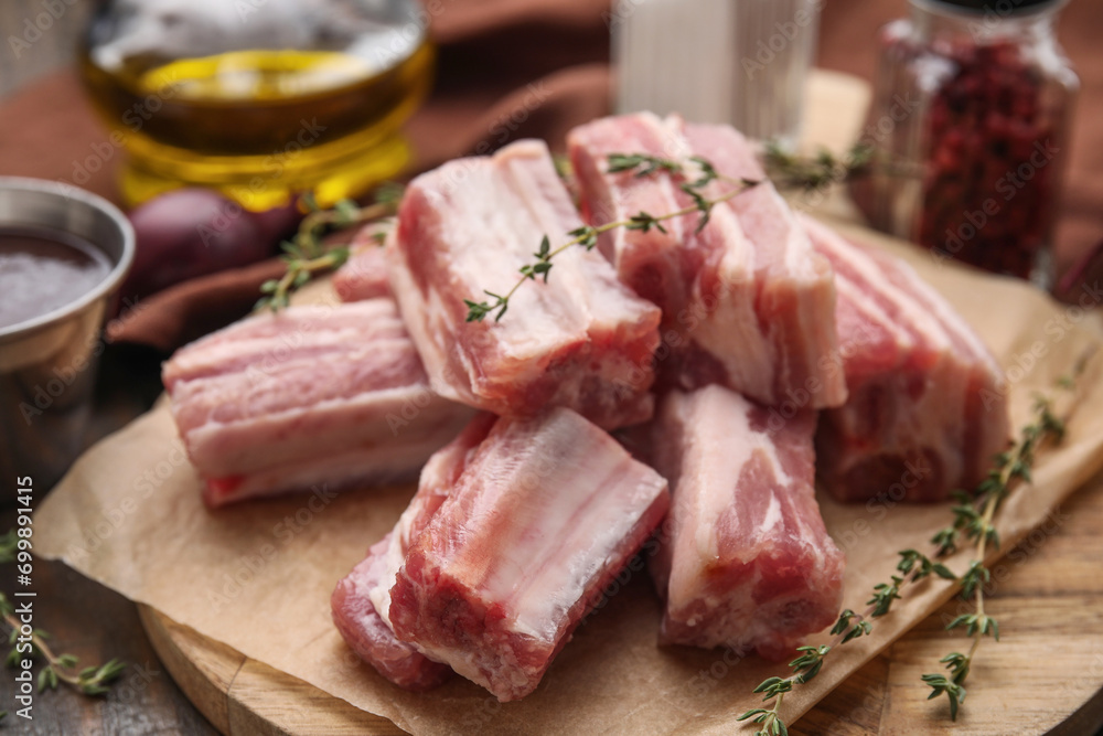 Cut raw pork ribs with thyme on table, closeup