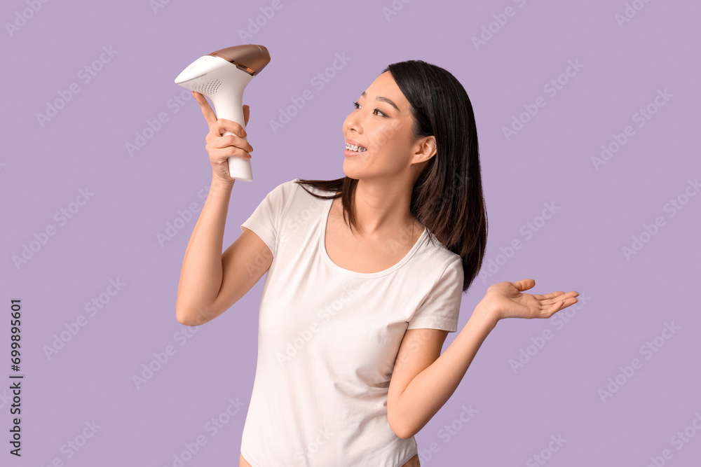Pretty Asian woman with photoepilator on lilac background Pretty Asian woman with photoepilator on lilac background
