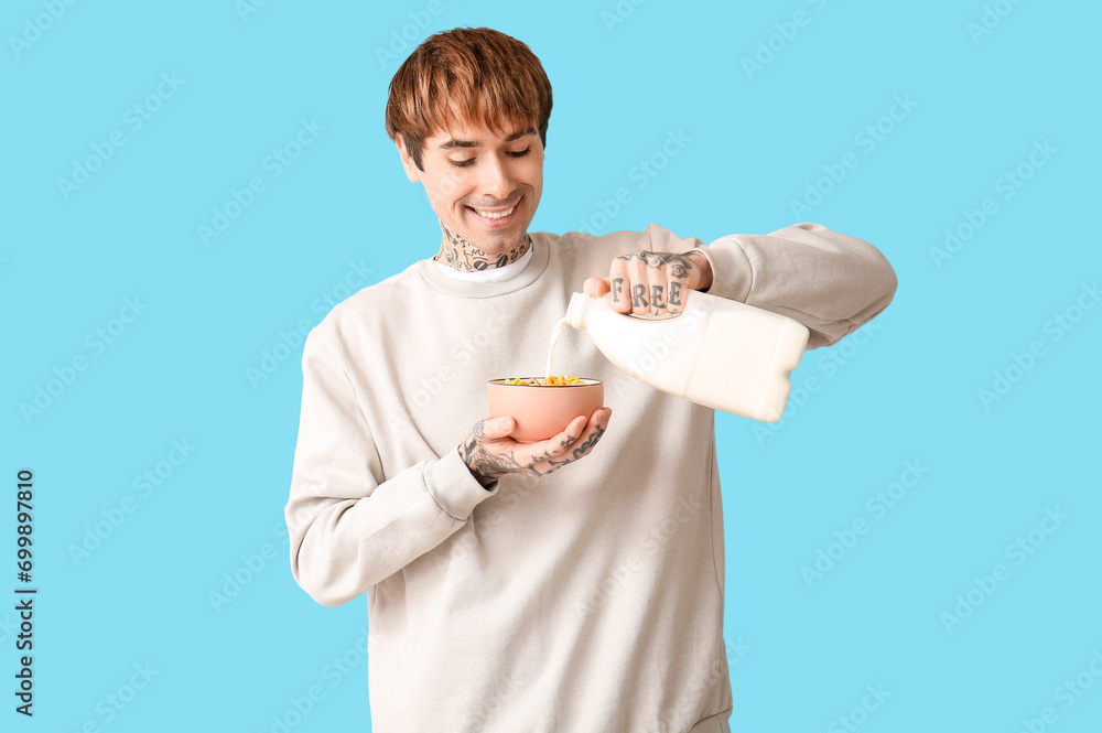 Man pouring milk into bowl with cereal rings on blue background Man pouring milk into bowl with cereal rings on blue background
