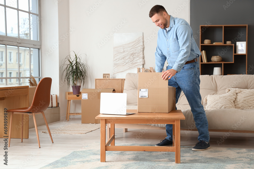Young man unpacking parcel on table at home Young man unpacking parcel on table at home