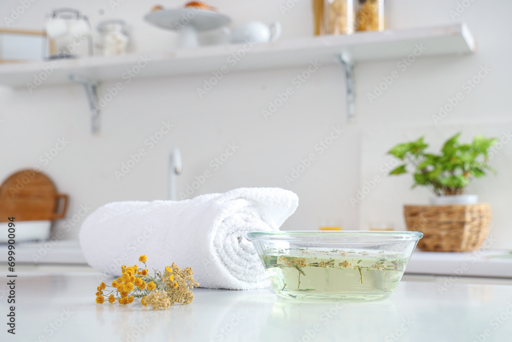 Steam inhalation with herbs and towel on table in kitchen, closeup Steam inhalation with herbs and towel on table in kitchen, closeup