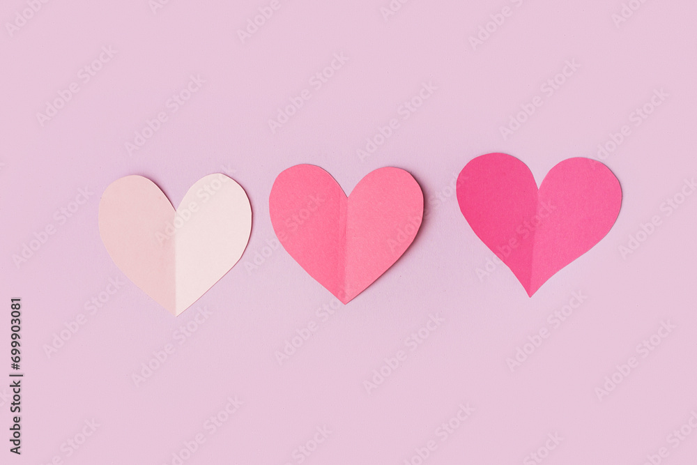 Pink paper hearts on lilac background. Valentine's Day celebration