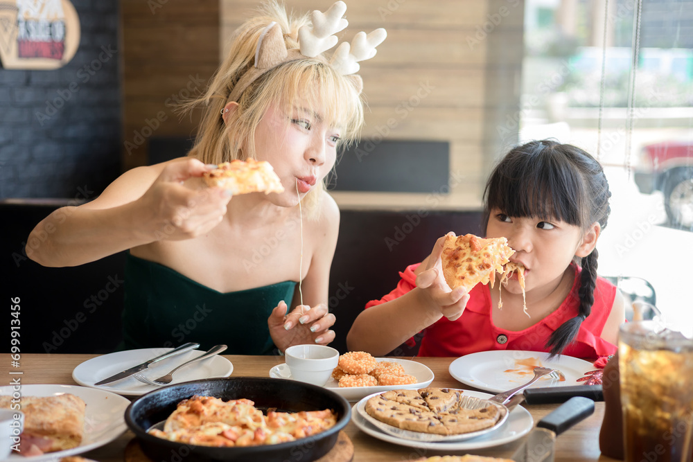 Happy mother and daughter Having Pizza in a Restaurant. Happy family craving for fast food meal Happy mother and daughter Having Pizza in a Restaurant. Happy family craving for fast food meal