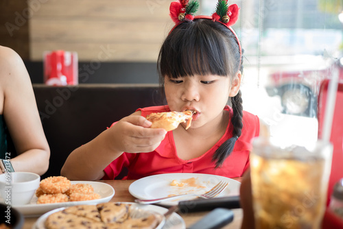 Happy asian little girl eat pizza on table at restaurant