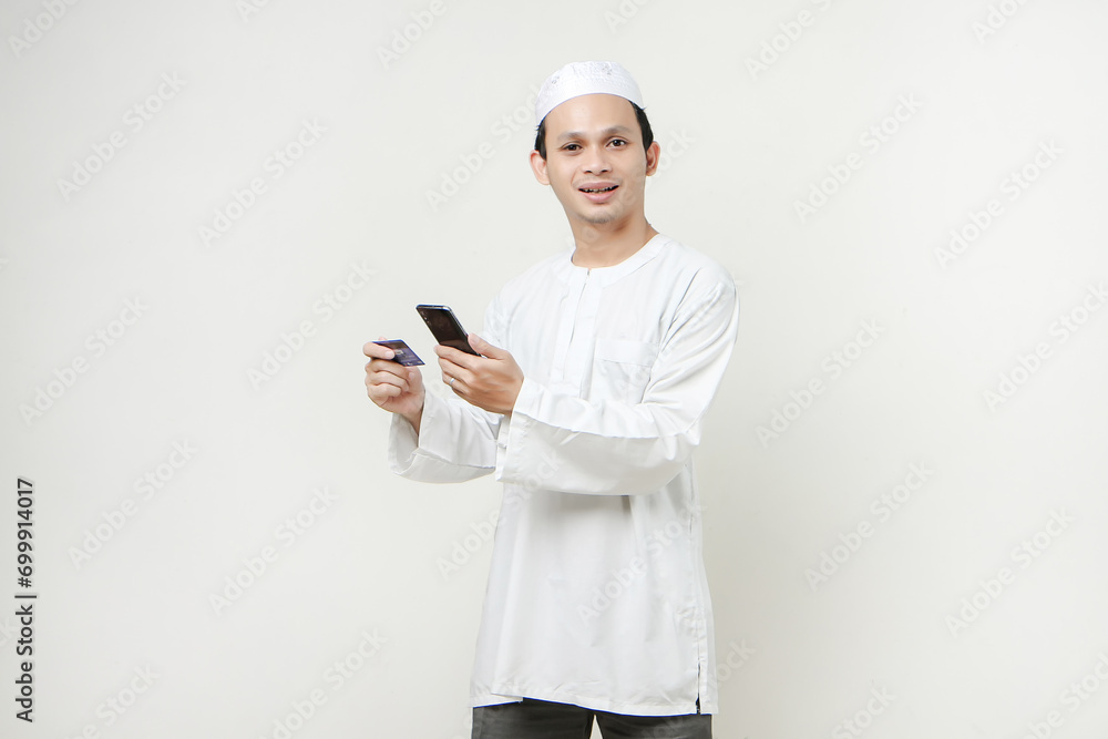 handsome asian man holding credit card and mobile phone on isolated background handsome asian man holding credit card and mobile phone on isolated background