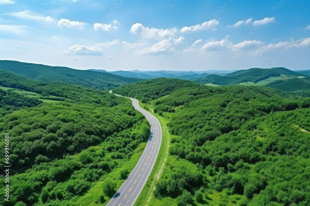 Aerial view of asphalt road and green forest, Beautiful fresh green natural scenery of hilltop. Healthy environment. Natural landscape.