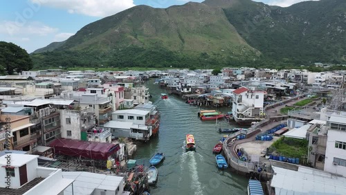 Aerial drone skyview of Tai O Fishing Village Touristic Boat Sailing in Canal,Lantau Island Hong Kong. Picturesque Island and Boats ply the waterway between stilts photo