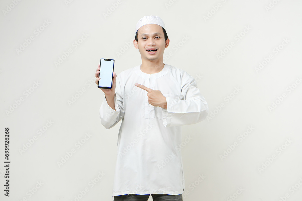 happy asian muslim showing blank phone screen and give pointing finger gesture. People religious Islam lifestyle concept. celebration Ramadan and ied Mubarak. on isolated background. happy asian muslim showing blank phone screen and give pointing finger gesture. People religious Islam lifestyle concept. celebration Ramadan and ied Mubarak. on isolated background.