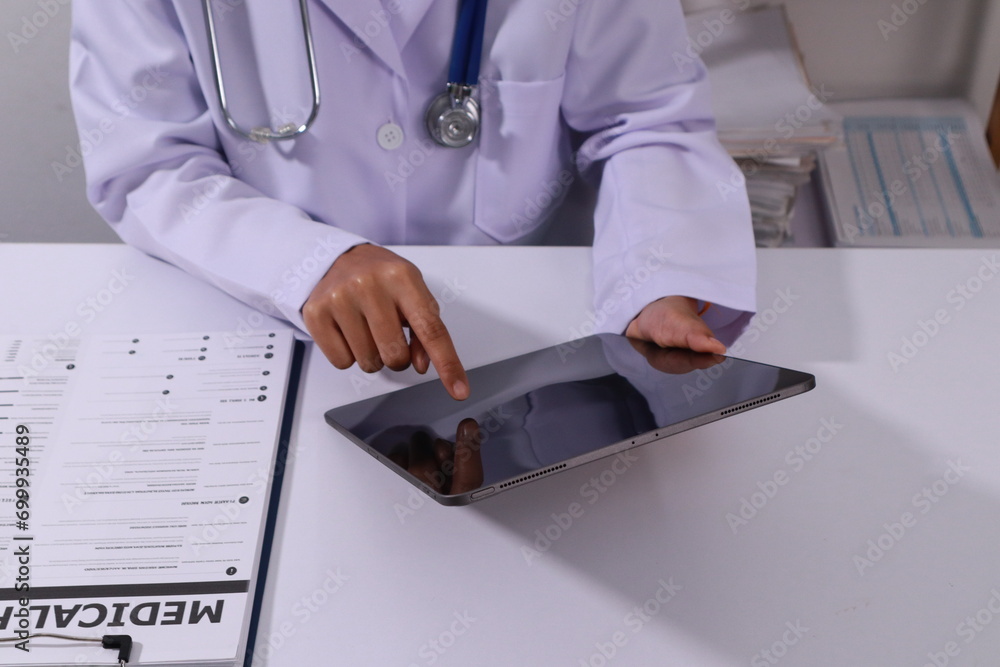 Fototapeta premium Close up of the ears of a professional female doctor in uniform taking notes in a notebook Medical therapist filling out medical documents. Clipboard. Patient form. Illness history, prescription