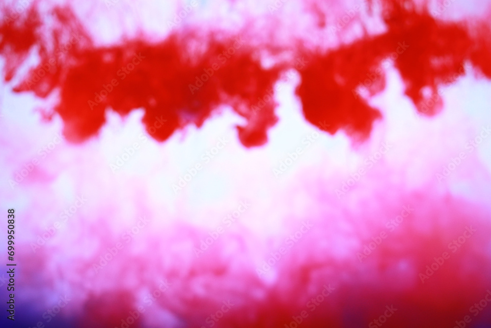 Blurred red color liquid ink pattern drop and swirling in water