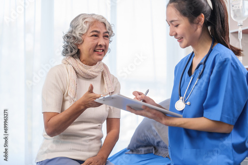 Health check concept  Elderly Asian woman with grey hair  sitting and talking to young Asian nurse by appointment  sitting on medical bed.