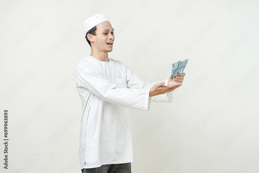 happy muslim man holding money rupiah banknotes. People religious Islam lifestyle concept. celebration Ramadan and ied Mubarak. on isolated background. happy muslim man holding money rupiah banknotes. People religious Islam lifestyle concept. celebration Ramadan and ied Mubarak. on isolated background.