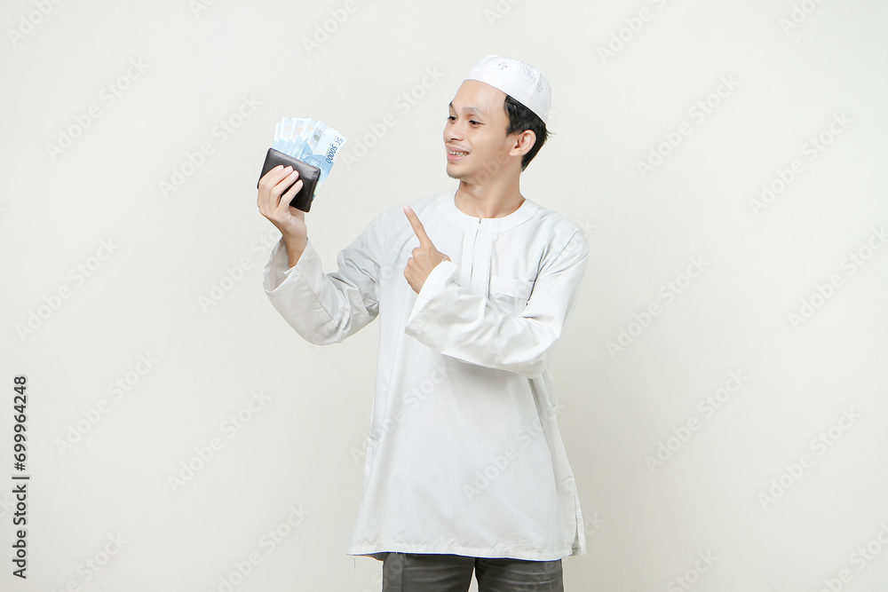muslim man holding money rupiah banknotes in the wallet and give pointinng finger gesture. People religious Islam lifestyle concept. celebration Ramadan and ied Mubarak. on isolated background. muslim man holding money rupiah banknotes in the wallet and give pointinng finger gesture. People religious Islam lifestyle concept. celebration Ramadan and ied Mubarak. on isolated background.