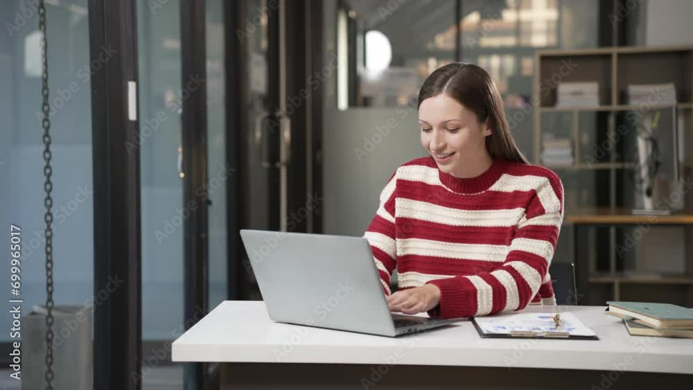 Woman wearing sweater sitting alone focusing on laptop computer and documents on counter with charts, many documents on table working overtime in office 4k 6op Woman wearing sweater sitting alone focusing on laptop computer and documents on counter with charts, many documents on table working overtime in office 4k 6op